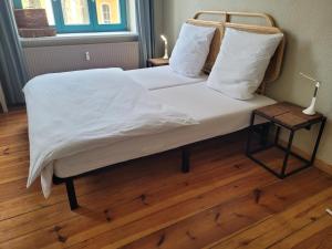 a bed with white sheets and pillows on a wooden floor at Lioba in Ueckermünde
