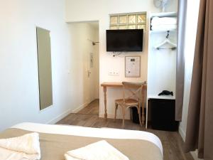 a bedroom with a desk and a tv on a wall at Hôtel Le Chantilly Deauville in Deauville