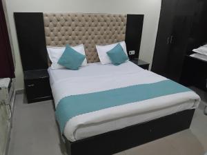 a bedroom with a large bed with blue pillows at Hotel Grand Inn in Haridwār