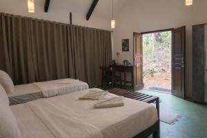 a bedroom with two beds and a window with a door at Nature's Nest Goa in Molem