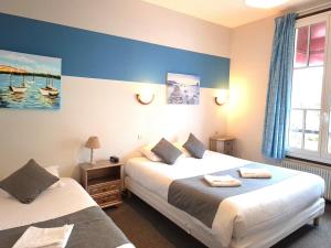 two beds in a room with blue walls at Hôtel Le Chantilly Deauville in Deauville