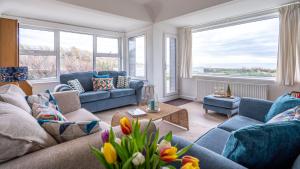 a living room with blue furniture and large windows at Borth Mawr in Rhosneigr