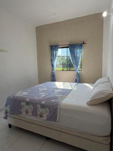 a bedroom with a bed with blue curtains and a window at JG&A Home in Itauguá