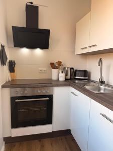 a kitchen with white cabinets and a sink and a stove at Artland Quartier Quakenbrück in Quakenbrück