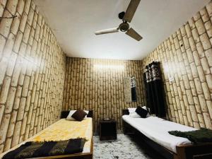 a bedroom with two beds and a ceiling fan at Krishna Villa in Varanasi