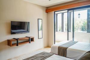 a bedroom with two beds and a flat screen tv at Jungle View Nest Selva Rooftop in Tulum