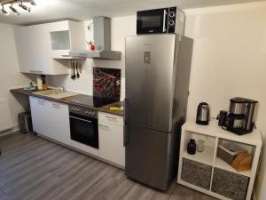 a kitchen with a stainless steel refrigerator and white cabinets at Fewo HARZ Benneckenstein in Benneckenstein +28 photos