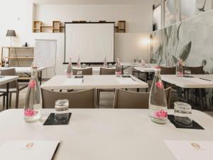 a classroom with tables and chairs and empty bottles at Kleos Hotel Milano Città Studi by Kleos Group Collection in Milan