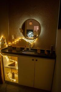 a bathroom with a sink and a mirror with lights at SP Hospedagem Canoa Quebrada in Canoa Quebrada