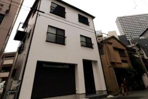 a white building with black windows and a garage at 龍宿 Noboru Yado in Kagoshima