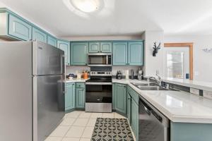 a kitchen with blue cabinets and a stainless steel refrigerator at 820 Badger Ln in Fraser +20 photos
