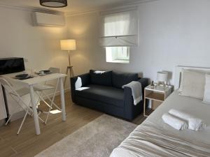 a bedroom with a bed and a couch and a desk at Modern Studio with Private Patio near Cascais & Sintra in Alcabideche