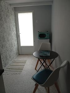 a room with a table and a chair and a microwave at Le studio des pins in Plouézec