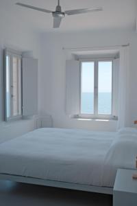 a white bedroom with a large bed and two windows at LELA'S in Kardamyli