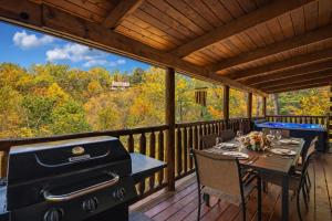 a screened in porch with a grill and a table and chairs at Bucky's Bungalow, Free Attraction Tickets, Hot Tub, WIFI!!! in Gatlinburg