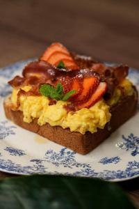 a piece of toast with eggs and bacon on a plate at WSCHODNIA ELEGANS Aparthotel in Łódź