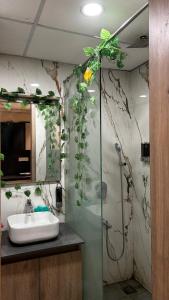 a bathroom with a sink and a shower with plants at Bee Home Stay in Greater Noida +1 photo