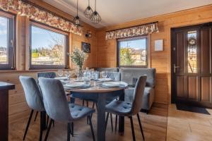 a dining room with a table and chairs and windows at Domek Przy Potoku Murzasichle in Murzasichle
