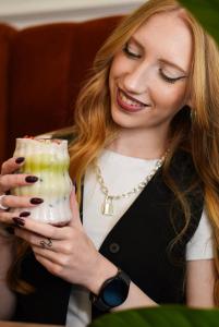 a woman is smiling while holding a drink at WSCHODNIA ELEGANS Aparthotel in Łódź