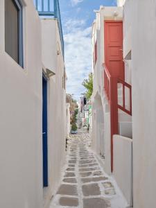a narrow alley with white buildings and a red door at Chiara Mykonos in Mikonos