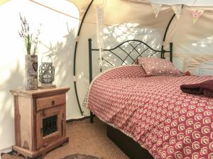 a bed with a red comforter and a wooden table at Shepherds Belle & Croft Hut - Qu7633 in Messing