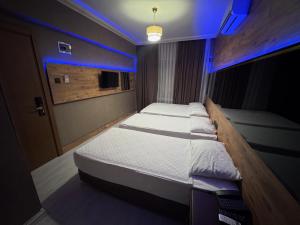 two beds in a room with blue lights at Temiz Hotel in Alanya