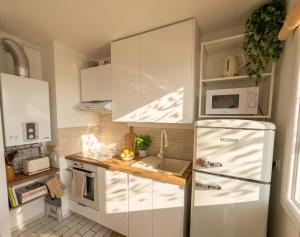 a kitchen with white cabinets and a refrigerator at Vue sublime-conciergrie IB in Canet-en-Roussillon