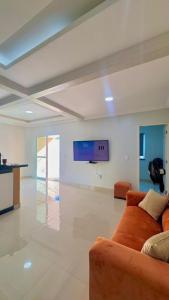 a living room with a couch and a flat screen tv at CASA MARIANNA em Paracuru - Piscina, 3 quartos, ar condicionado e perto de tudo! in Paracuru