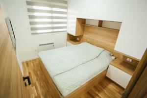 a small bed in a small room with wood floors at BK Apartman in Zlatibor +9 photos