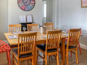 a dining room table with chairs and a clock on the wall at Tolcarne Retreat in Newquay