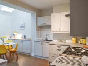 a kitchen with white cabinets and a table and a stove at Tolcarne Retreat in Newquay