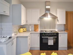 a kitchen with white cabinets and a black stove at Tolcarne Retreat in Newquay