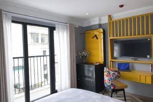 a bedroom with a bed and a television and a chair at Hanora Boutique Hotel in Hanoi