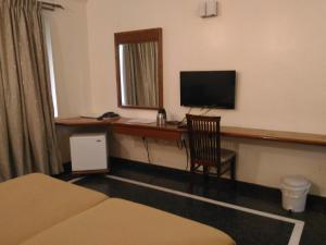 a room with a desk with a television and a chair at Woody's in Bangalore