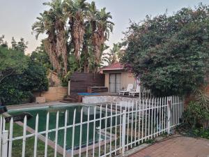 a house with a white fence and a swimming pool at Dream Big Bougainvillea 2 bedroom cottage in Centurion