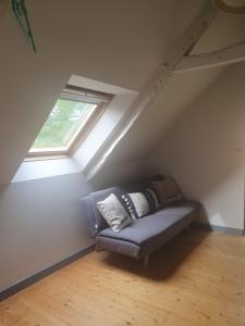 a couch in a attic with a window at Au chat qui pêche in Pléguien
