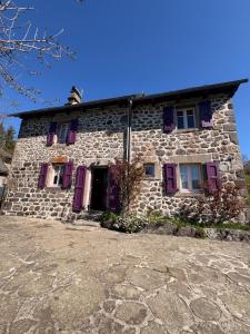 an old stone house with purple doors and windows at Nouveau - Maison Nierveze proche Lioran in Thiézac