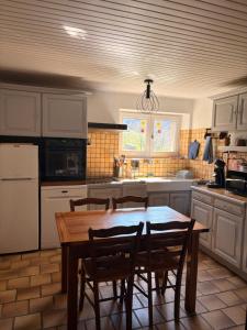 a kitchen with a wooden table and chairs in it at Nouveau - Maison Nierveze proche Lioran in Thiézac
