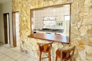 a kitchen with a stone wall with a table and chairs at Residencial Zirke in Florianópolis