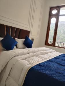 a large bed with blue and white sheets and a window at Velley inn hotel & resort in Barkot +16 photos