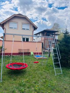 three swings in a yard in front of a house at Alex Vip Apartman in Hajdúszoboszló
