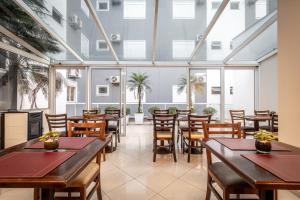 a restaurant with tables and chairs and windows at Hotel Kindermann in Caçador