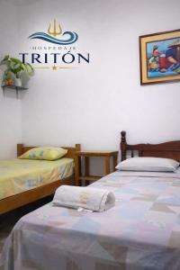 two beds in a room with a sign on the wall at Casa de Playa Triton in Máncora