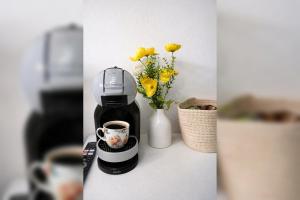 a coffee maker and a cup on a counter with flowers at Acqua & Luce in Meina