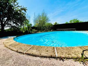 a large pool with blue water in a yard at Petite maison Cosy Le gaucher in Muret