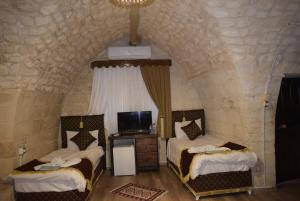 a bedroom with two beds and a tv in it at JOSELİN HOTEL in Urfa