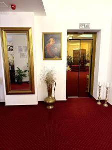 a hallway with a painting and a vase on a red carpet at Hotel Sebastian u Hoffera in Modra