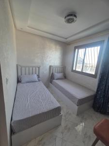 a bedroom with two beds and a window at Appartement rif roayal in Al Hoceïma