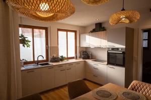 a kitchen with white cabinets and a table and some lights at Boho vibes between mountains and lakes in Schlier