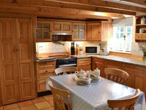 a kitchen with wooden cabinets and a table with chairs at Condurrow Cottage in Saint Anthony